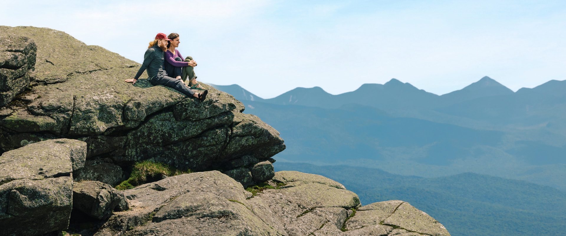 A couple sits on top of Whiteface Mountain admiring the views